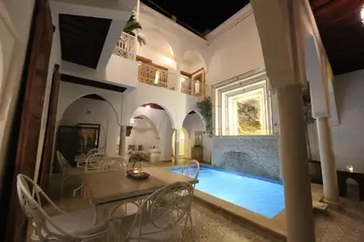 a living room with a table and a swimming pool at Riad Oum h&N in Srarhna