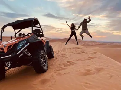 a man and a woman jumping in the desert next to at kasbah estrella in Merzouga