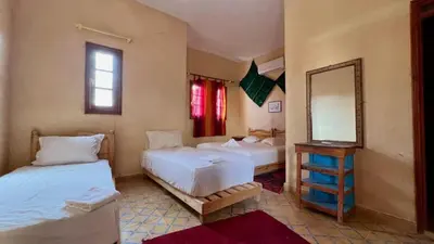a bedroom with two beds and a mirror in it at kasbah estrella in Merzouga