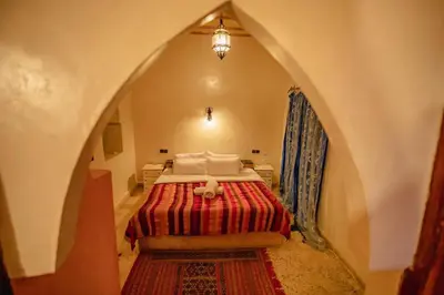 a bedroom with a bed with a red blanket at kasbah estrella in Merzouga