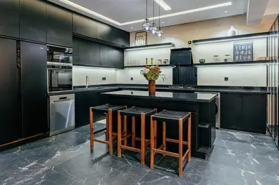 a kitchen with black cabinets and a table with stools at Stunning luxury Villa with Mountain Views in Sbiti
