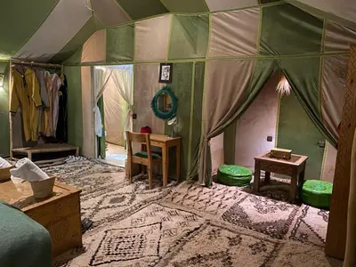 a room with a tent with a table and chairs at Magamane luxury camp in Merzouga