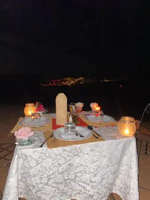 a table with plates of food and candles on it at Magamane luxury camp in Merzouga
