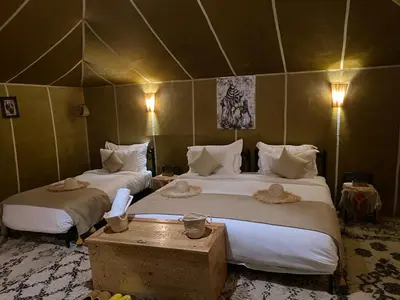 a hotel room with two beds and a table at Magamane luxury camp in Merzouga