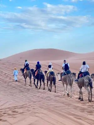 a group of people riding horses in the desert at Magamane luxury camp in Merzouga