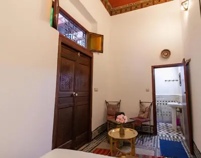 a room with a door and a table and chairs at Dar bab jdid Rcif- step away from historic sites in Fès