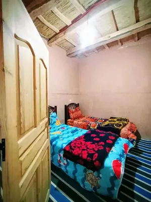 a bedroom with two beds in it with a bedskirts at Auberge le calme restaurante in Bou Tharar