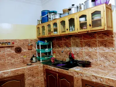 a kitchen with a sink and cabinets with pots and pans at Auberge le calme restaurante in Bou Tharar