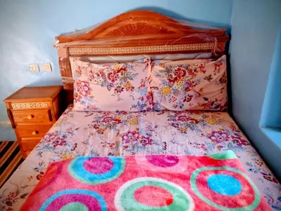 a bed with a colorful bedspread and pillows on it at Auberge le calme restaurante in Bou Tharar