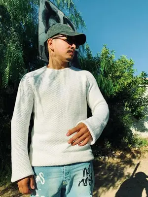a young man wearing a white sweater and a hat at Dar sonic in Ouarzazate