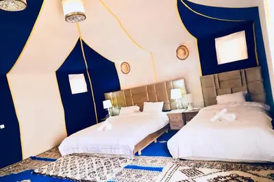 two beds in a bedroom with blue and white walls at Tenere Luxury Camp in Merzouga