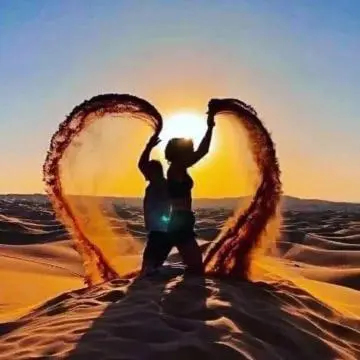 a person standing in the desert with two heart shaped signs at Tenere Luxury Camp in Merzouga
