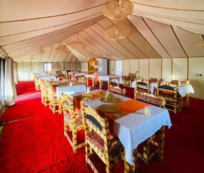 a dining room with tables and chairs in a tent at Itran luxury camp in Merzouga