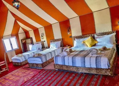 a bedroom with three beds and a striped wall at Itran luxury camp in Merzouga