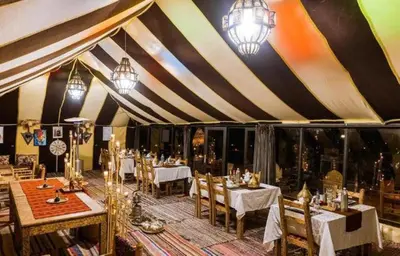 a dining room with tables and chairs in a tent at Itran luxury camp in Merzouga