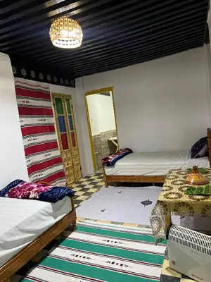 a room with two beds and a table at chembre Naima mbarki in Fès