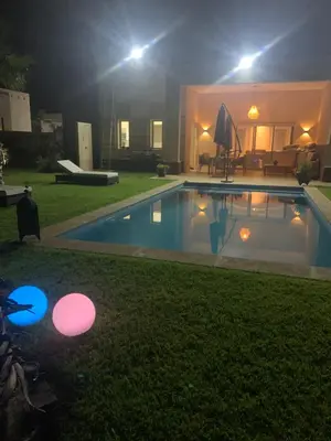 a backyard with a swimming pool at night at Villa à Marrakech-avec piscine privėe in Douar Soukkane