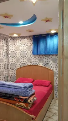 a bedroom with a bed with red sheets and blue curtains at Dar Bouchikhi in Moulay Yacoub