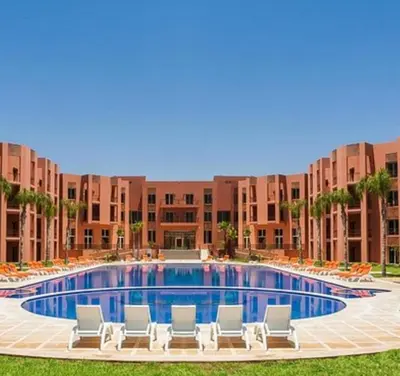 a large swimming pool with lounge chairs in front of a building at slimane in Aït Hallouane