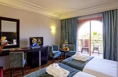 a hotel room with two beds and a desk and a window at slimane in Aït Hallouane