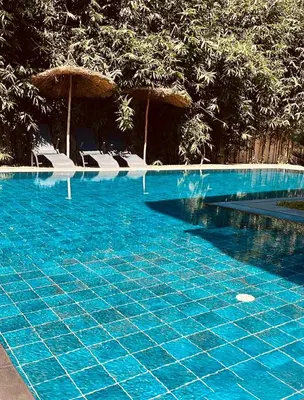 a blue swimming pool with chairs and umbrellas at Villa 3chambres Aéroport de Fès Piscine Jacuzzi in Oulad Tayeb