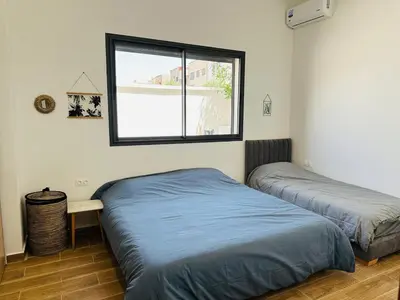 two beds in a room with a window at Villa 3chambres Aéroport de Fès Piscine Jacuzzi in Oulad Tayeb