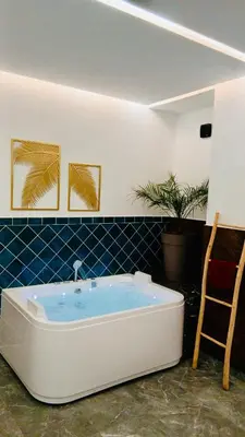 a bath tub in a room with a chair at Villa 3chambres Aéroport de Fès Piscine Jacuzzi in Oulad Tayeb