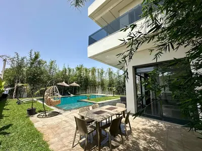 a backyard with a table and a swimming pool at Villa 3chambres Aéroport de Fès Piscine Jacuzzi in Oulad Tayeb