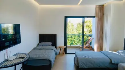 two beds in a room with a tv and a balcony at Résidence Fès Garden Piscine privé ou Jacuzzi in Oulad Tayeb