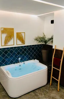 a bath tub in a room with a chair at Résidence Fès Garden Piscine privé ou Jacuzzi in Oulad Tayeb