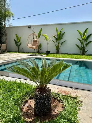a palm tree in front of a swimming pool at Résidence Fès Garden Piscine privé ou Jacuzzi in Oulad Tayeb