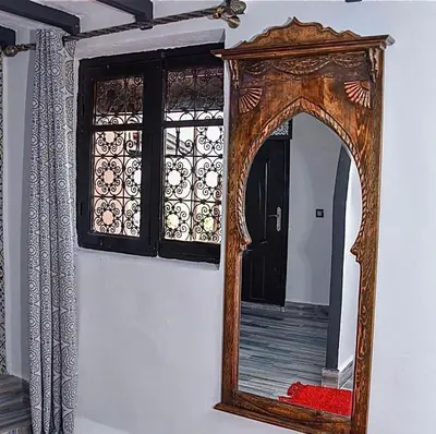 a mirror with a wooden frame on a wall at Tynass Ferme - Fes in Fès
