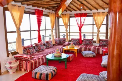 a living room with couches and tables and windows at Tynass Ferme - Fes in Fès