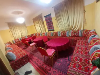 a living room with a couch with red tables and chairs at Asmaa Guesthouse Todra in Tinerhir