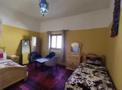 a bedroom with two beds and a desk and a mirror at Asmaa Guesthouse Todra in Tinerhir