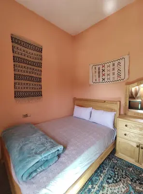 a small bedroom with a bed and a dresser at Asmaa Guesthouse Todra in Tinerhir