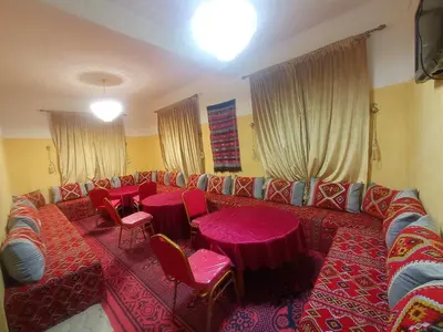 a living room with a couch and tables and chairs at Asmaa Guesthouse Todra in Tinerhir