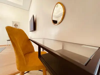 a glass table with a yellow chair and a mirror at Zyon Family in Oulad Akkou