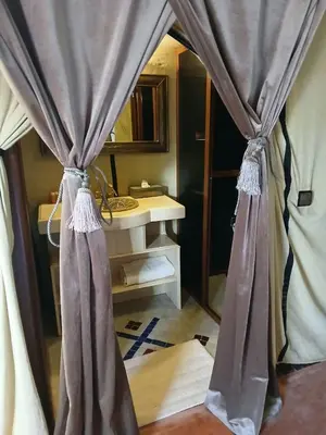a room with a bed with curtains and a table at Amandesertcamp in Lac Yasmins