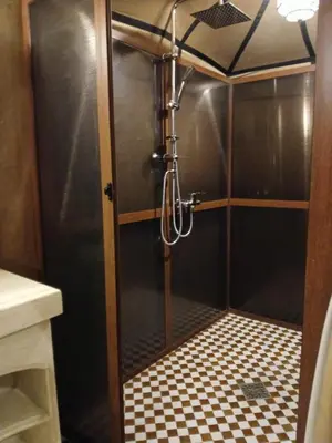 a shower with a glass door with a checkered floor at Amandesertcamp in Lac Yasmins
