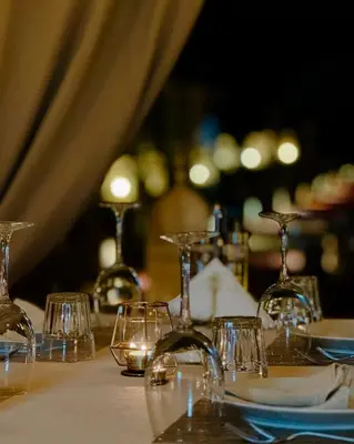 a table with wine glasses on a table at Zeus Sahara Luxury Camp in Merzouga