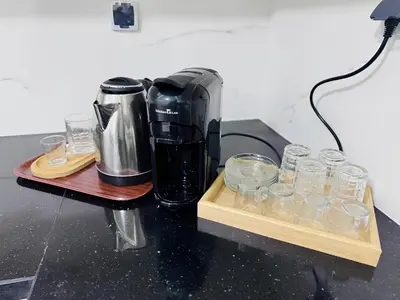 a coffee maker sitting on a table with glasses at URBAN WHITE Elya 2 in Beni Mellal