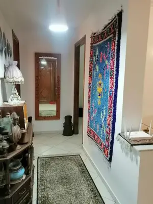 a living room with a rug on the wall and a tapestry at complex mousse in Oulad Akkou