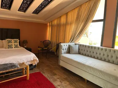 a bedroom with a bed and a couch and a window at Tynass Ferme - Chambre Zalagh Fes