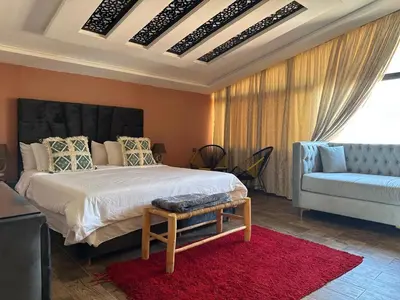 a bedroom with a bed and a couch and a red rug at Tynass Ferme - Chambre Zalagh Fes