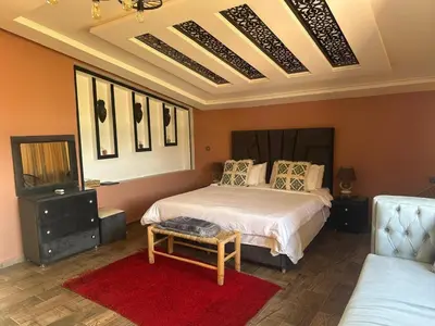 a bedroom with a bed and a red rug at Tynass Ferme - Chambre Zalagh Fes