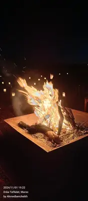 a fire in a wooden table with flames at Daraa Valley House in Mhamid