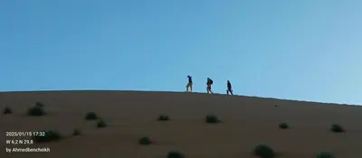 three people standing on top of a hill in the desert at Daraa Valley House in Mhamid