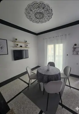 a dining room with a table and chairs and a television at Appartement 3S in Meknès