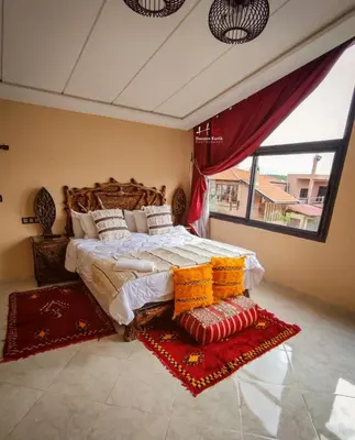 a bedroom with a large bed and a large window at Tynass Ferme - Atlas Room Fes